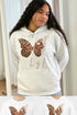 Person wearing a white hoodie with a butterfly design and &